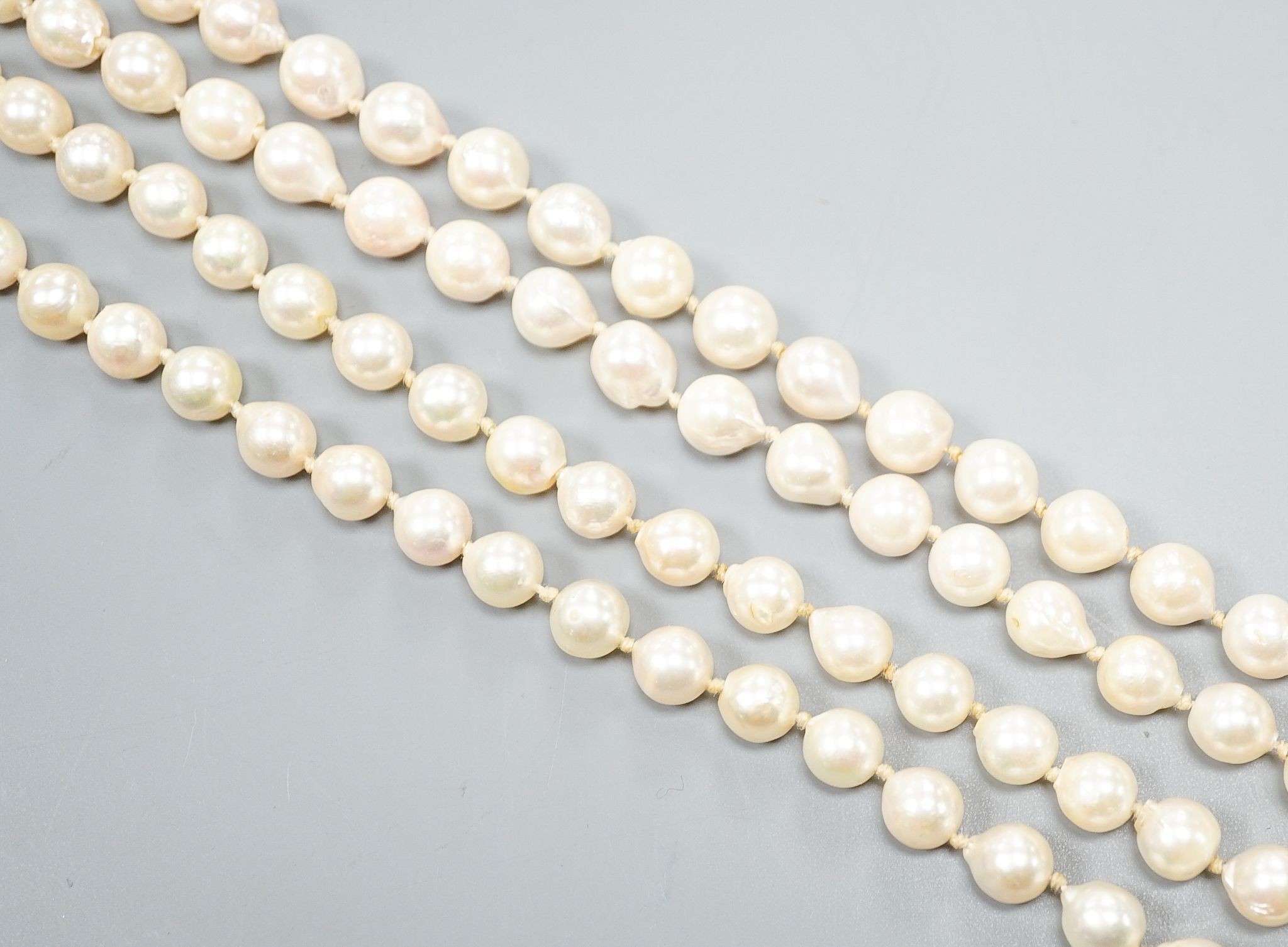 A modern long single strand cultured pearl necklace, with fluted 14k and diamond chip set clasp, 116cm.